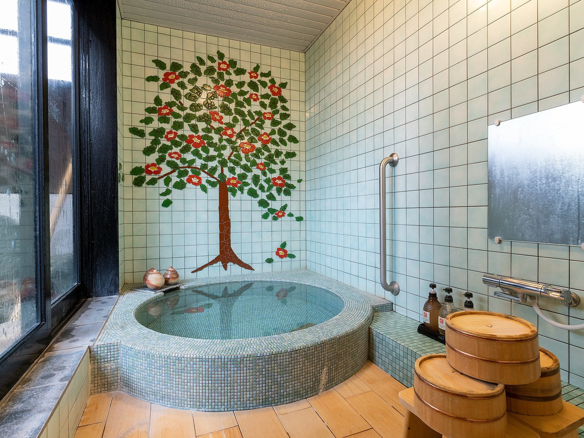 A tiled bath with a decorative tree mural.