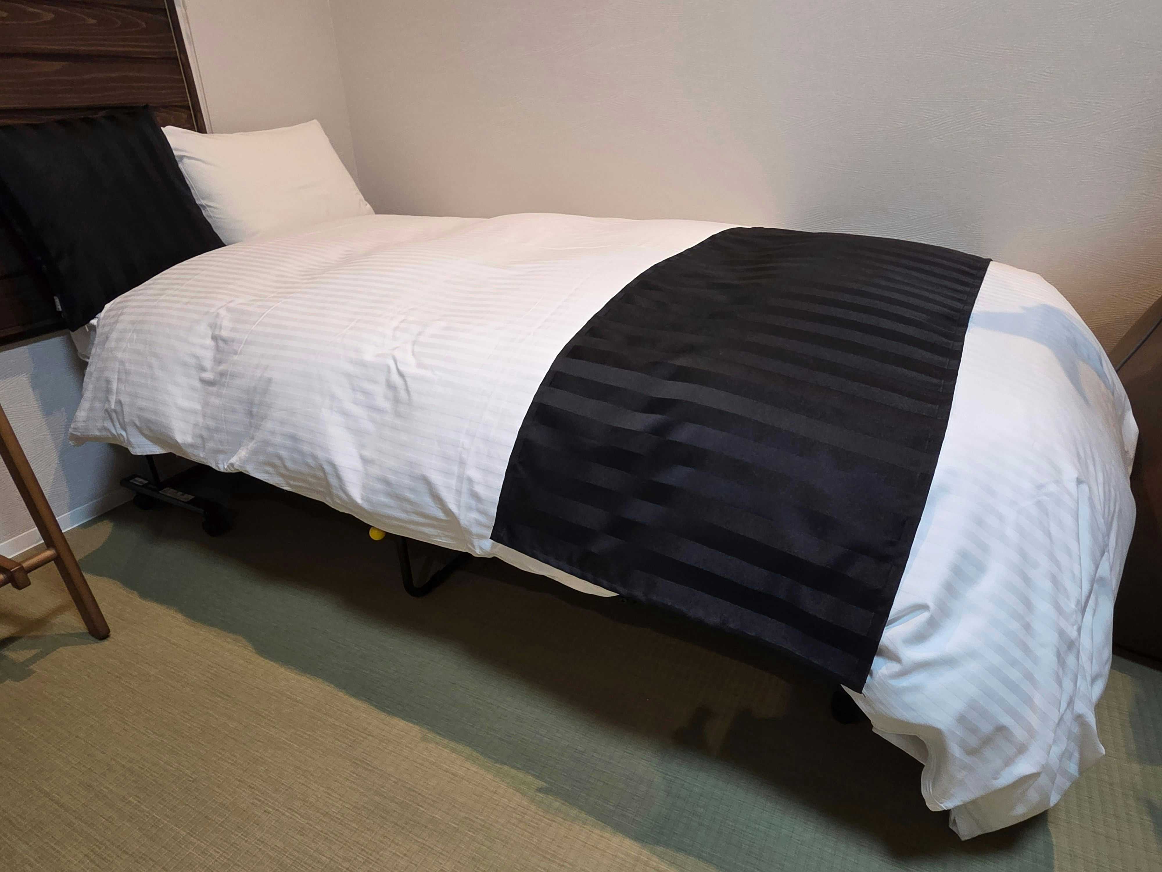 Ryokan Yamato-ya with a single bedroom with black runner and sloping ceiling.