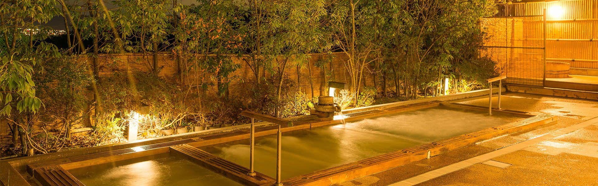 Sato-yu Mukashibanashi Yuzanso with an open-air hot spring bath surrounded by bamboo and garden lighting.