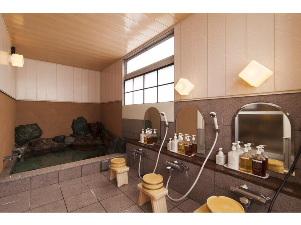 Indoor bath with rocks and a shower area.