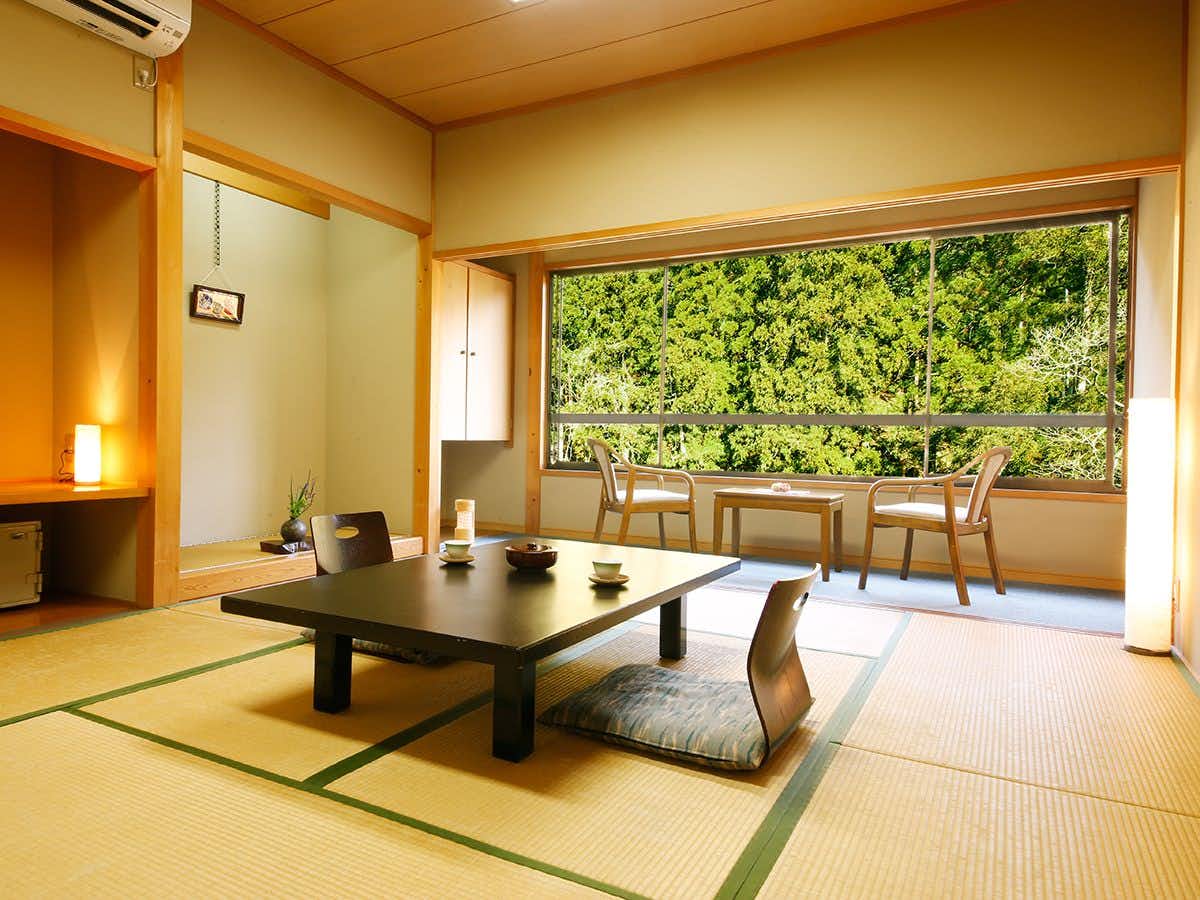 Kyoto Miyama Ryokan Makuragawa with a traditional tatami room facing dense forest greenery.