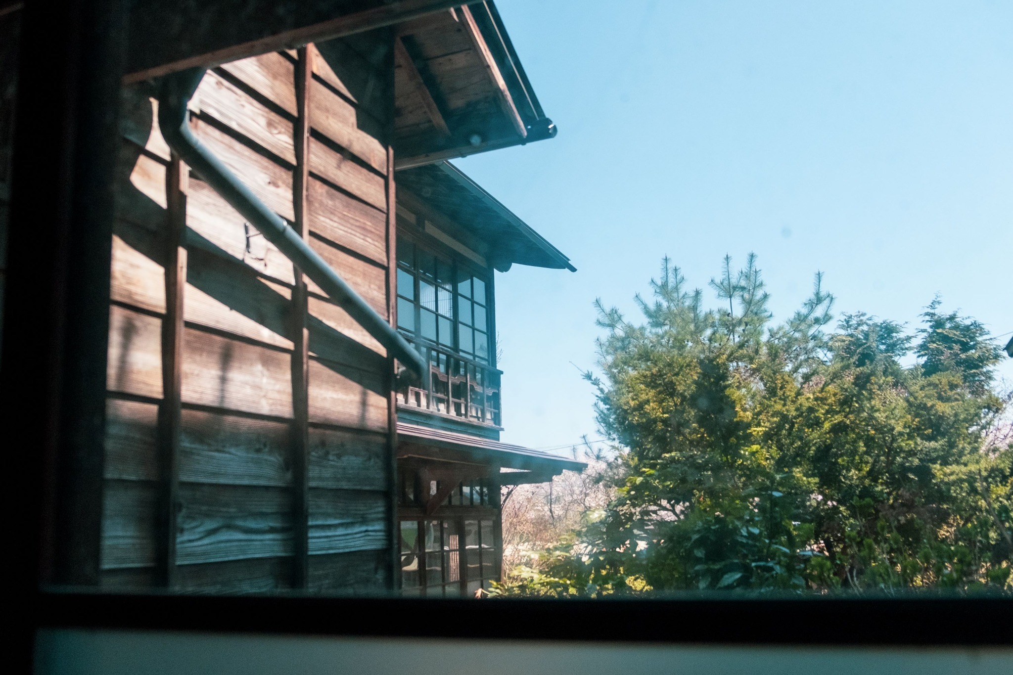 A traditional wooden exterior is framed by greenery.