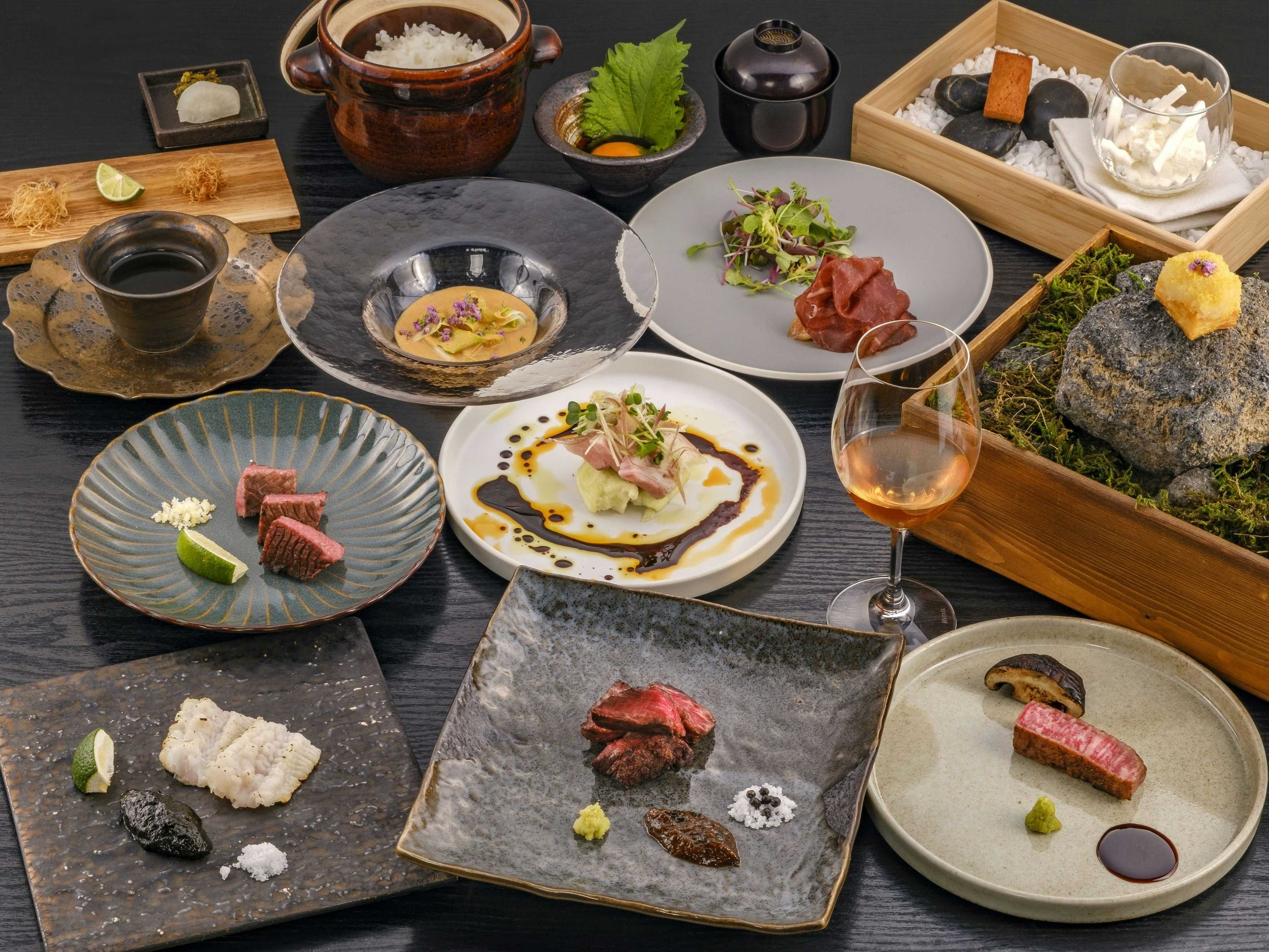 Nagui-kan Annex Tamayura with a multicourse dinner arranged across dark stone and ceramic plates.