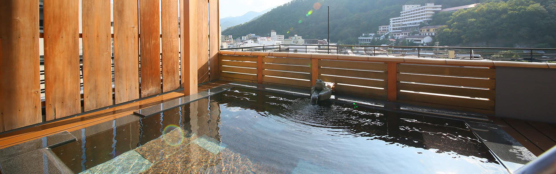 Togura Kamiyamada Onsen Ogiwara-kan with an open-air mineral bath overlooking forested mountains.