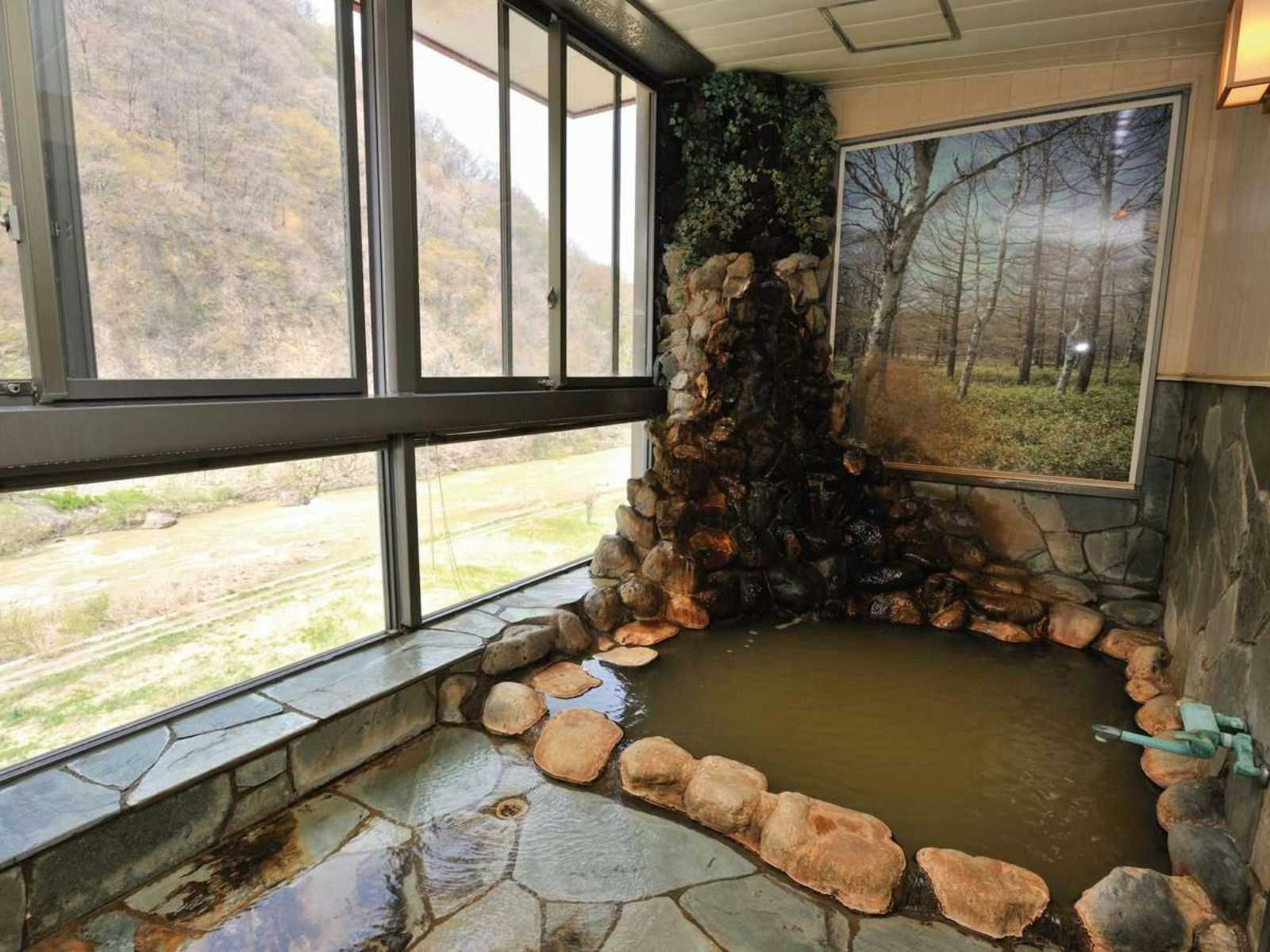 Susobana Gorge Natural Hot Spring Inn Uruoi-kan with an indoor rock bath overlooking the wooded gorge.