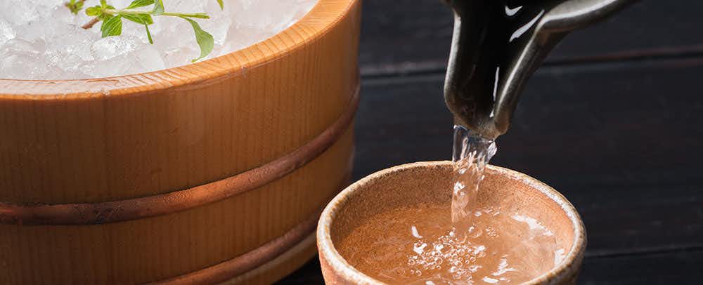 Hanare no Yado Waraku Wooden basin with water flowing and splashing, metal spout visible above.