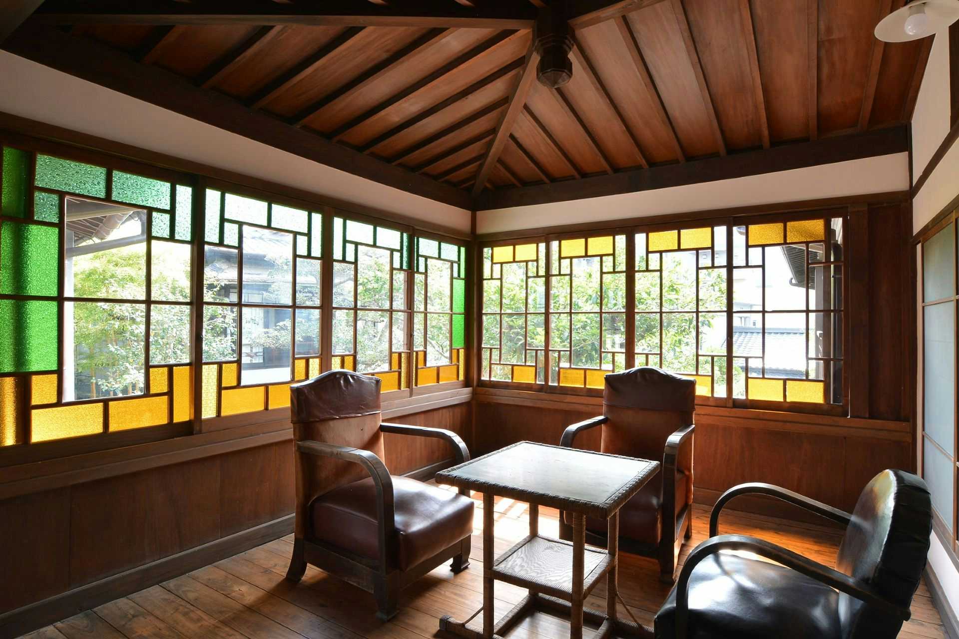 Yoshino Ryokan, a National Registered Tangible Cultural Property Inn, Hitoyoshi Onsen with a heritage lounge glowing through geometric stained glass.