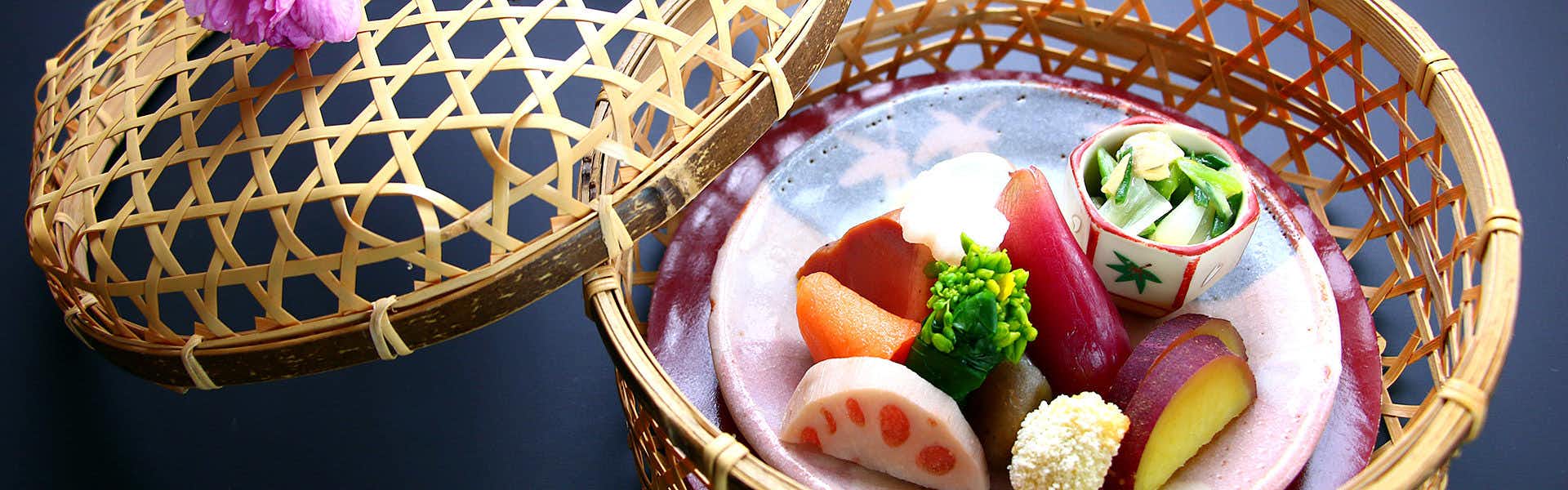 Marucho Ryokan Woven baskets present a pink dish displaying sliced and shaped prepared items arranged with garnish in varied tones.