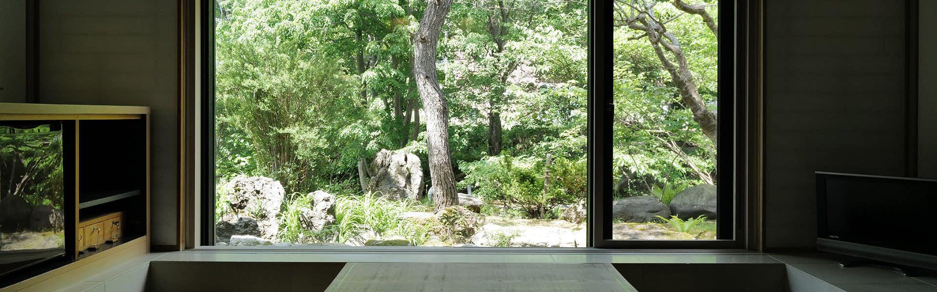 Otaru Ryotei Kuramure with a minimalist tatami lounge overlooking a green forest.