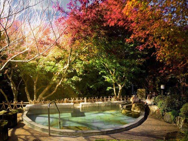 Takimien circular outdoor bath beneath red-leaved trees and wooden railings