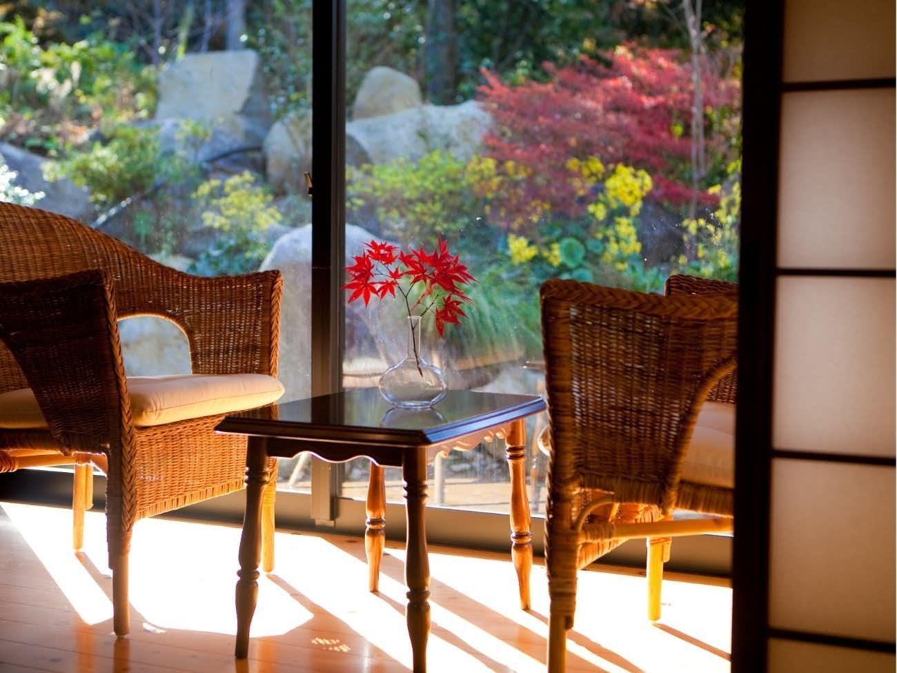 Kogane Onsen Kogane Sanso with a quiet window lounge with wicker chairs and autumn foliage.