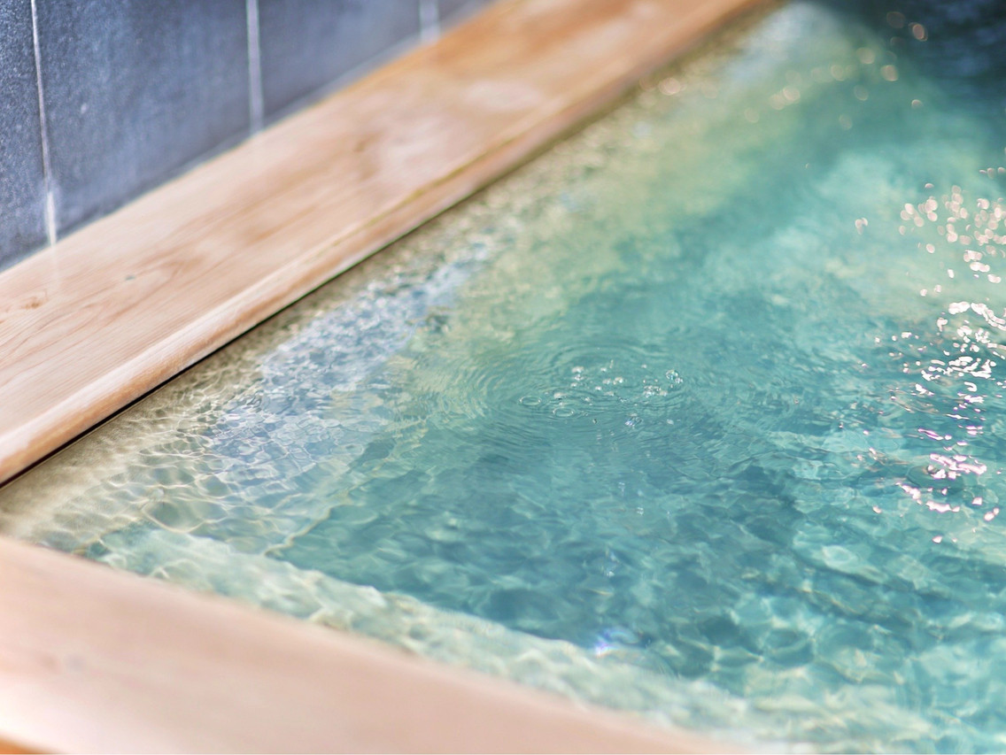 Clear rippling bathwater beside a wooden bath edge.