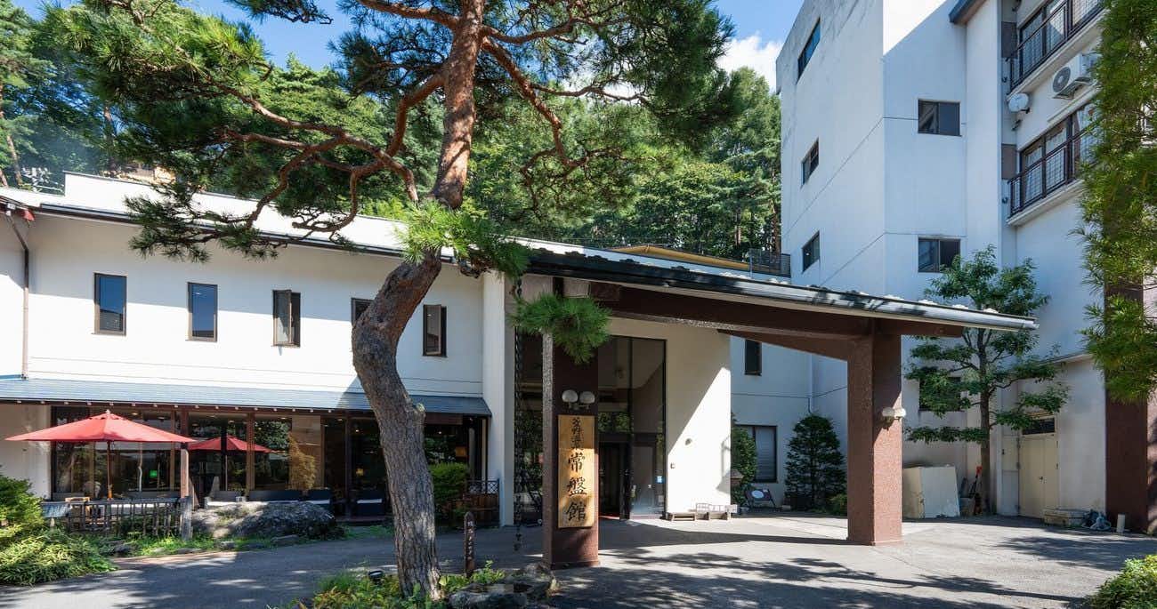 Hishino Onsen Tokiwakan with the white hillside building framed by sculpted pine trees.