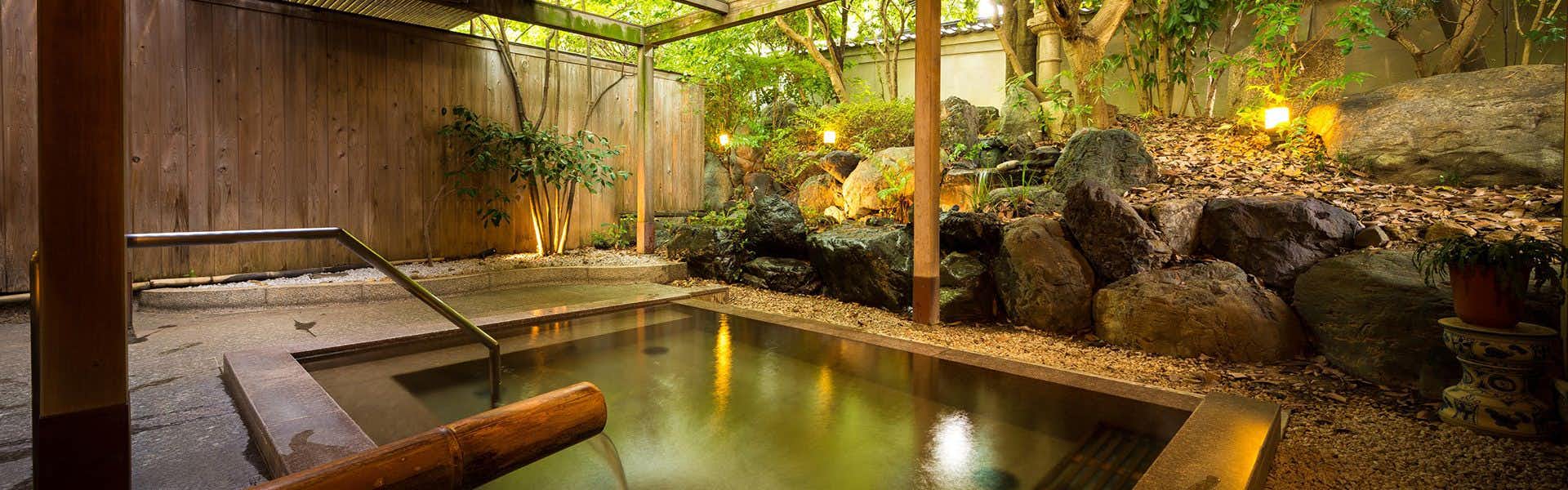 Kasuga Hotel with an outdoor garden bath surrounded by bamboo and rocks.
