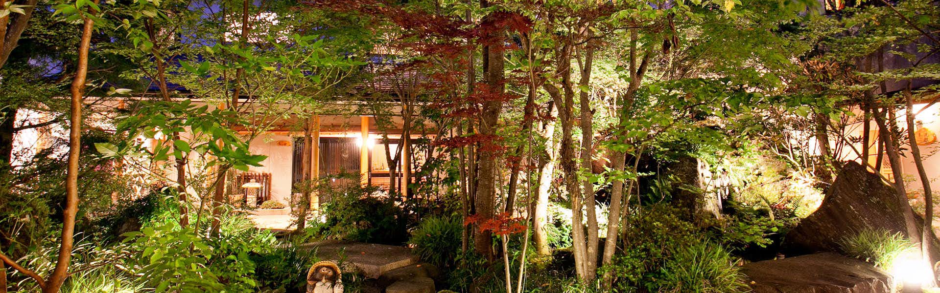 Tabisou Yufuin Yamadaya with the traditional inn illuminated within a woodland garden.
