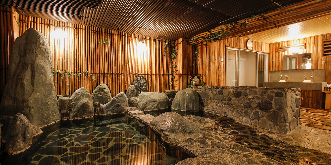 Genroku Hatago Aburaya with this scene, where its rock-lined indoor bath is wrapped in warm timber and bamboo.