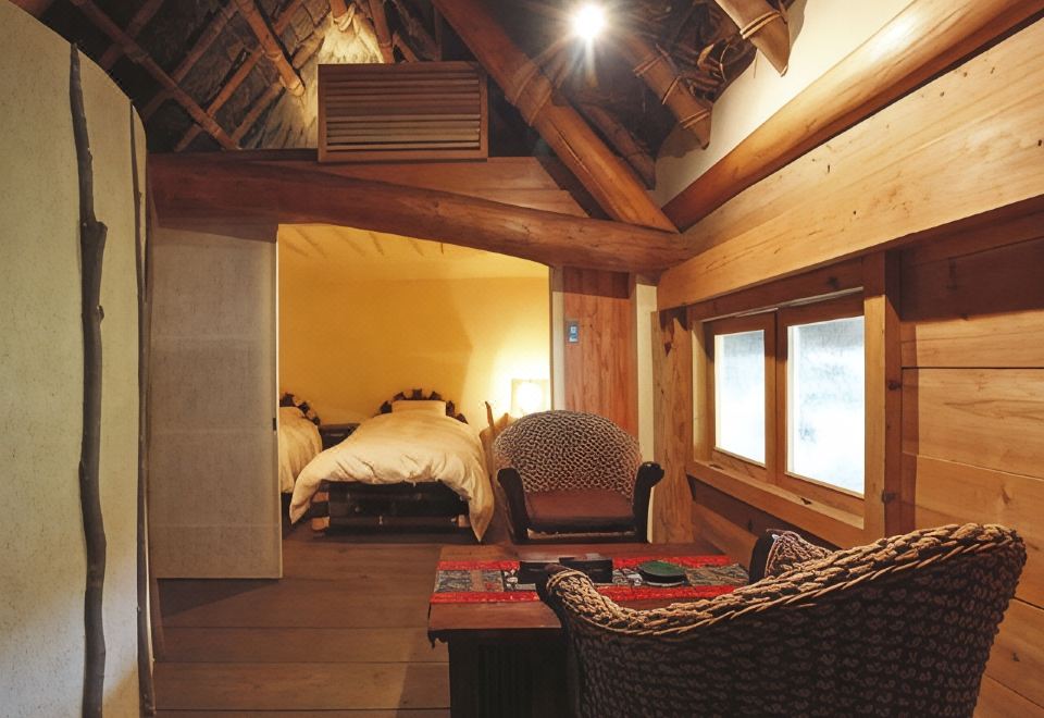 A wood-paneled guest room with a bed and chairs.