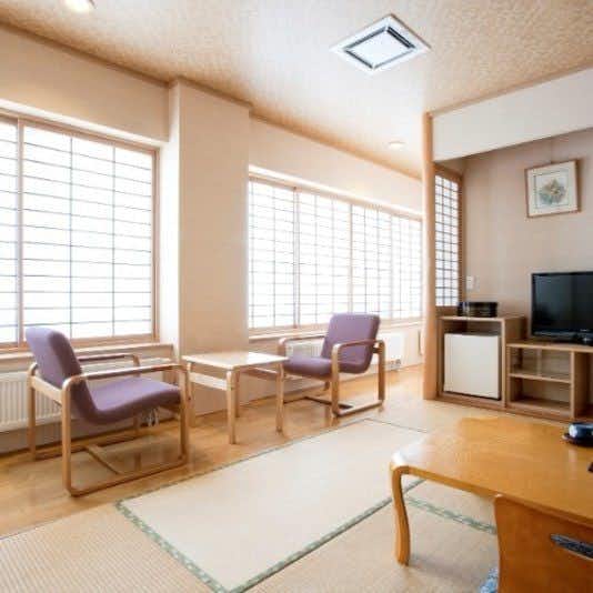 Noboribetsu Karurus Onsen Yumoto Orofureso with a bright tatami sitting room with two chairs and a television.