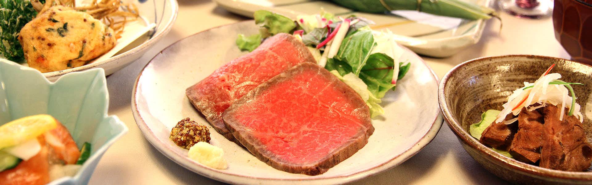 Yama no Tabisha Nakaodaira plate of prepared items and greens arranged on a dark tabletop