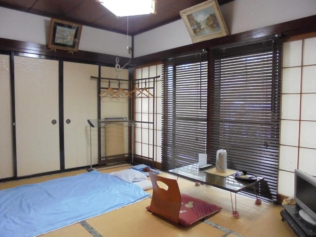 Tamonkan with a simple tatami room with folded blue bedding.