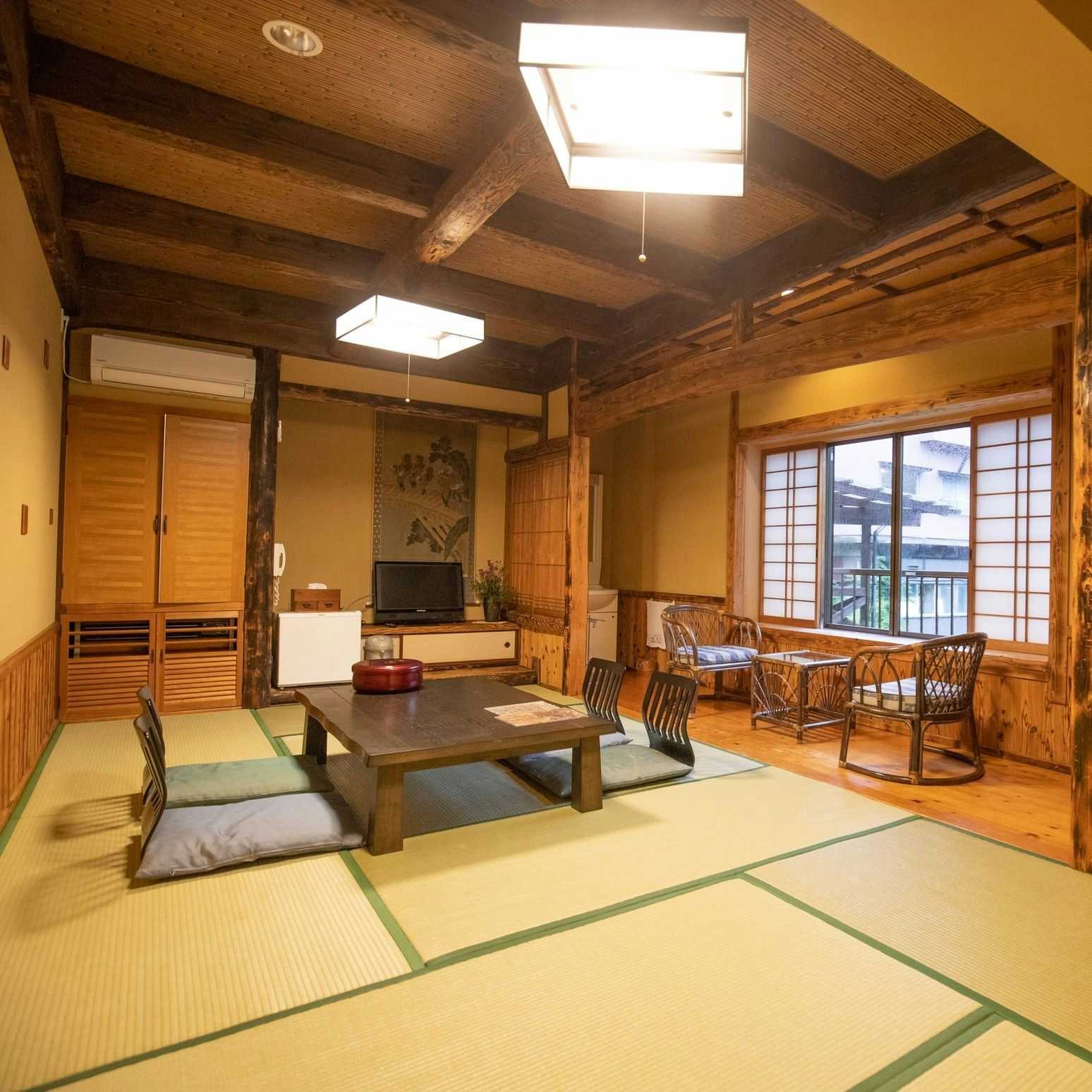 Kuyuspa Onsen Ryokan Seifuso with a warm tatami room with exposed beams and window seating.