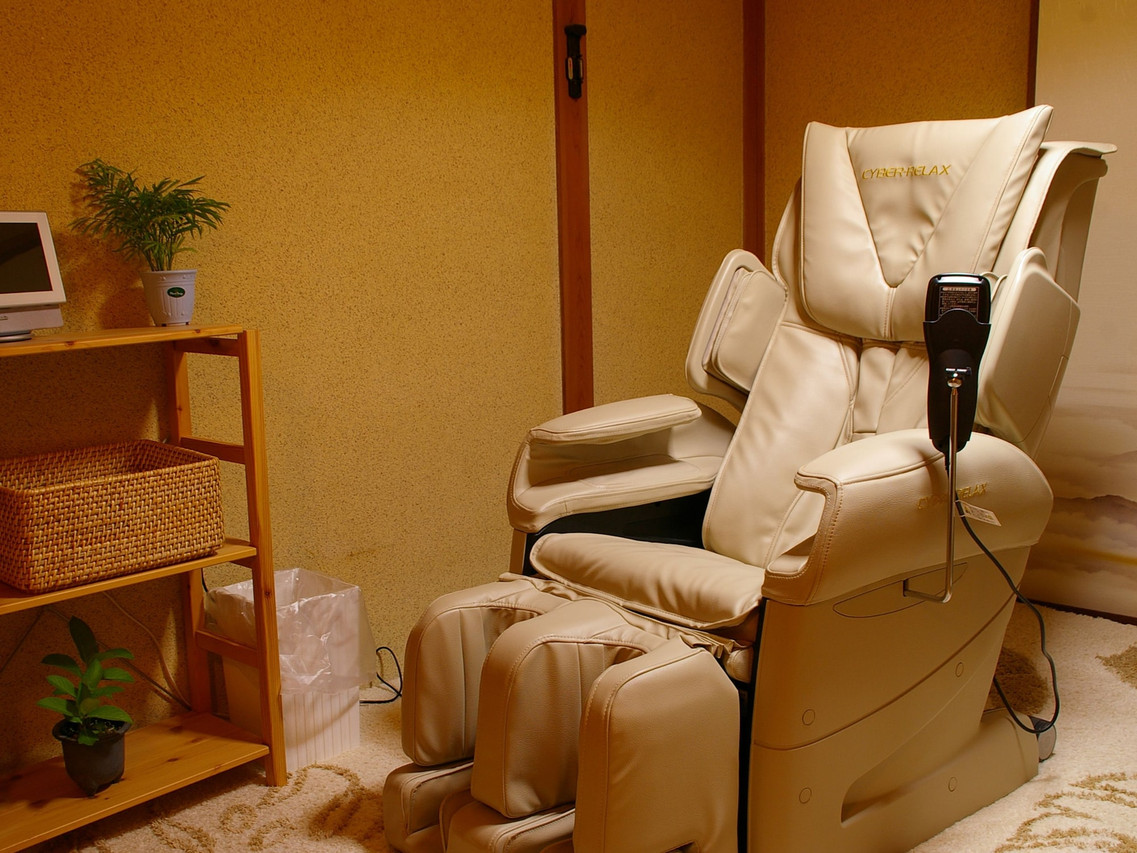 A massage chair sits in a warm wood-lined room.