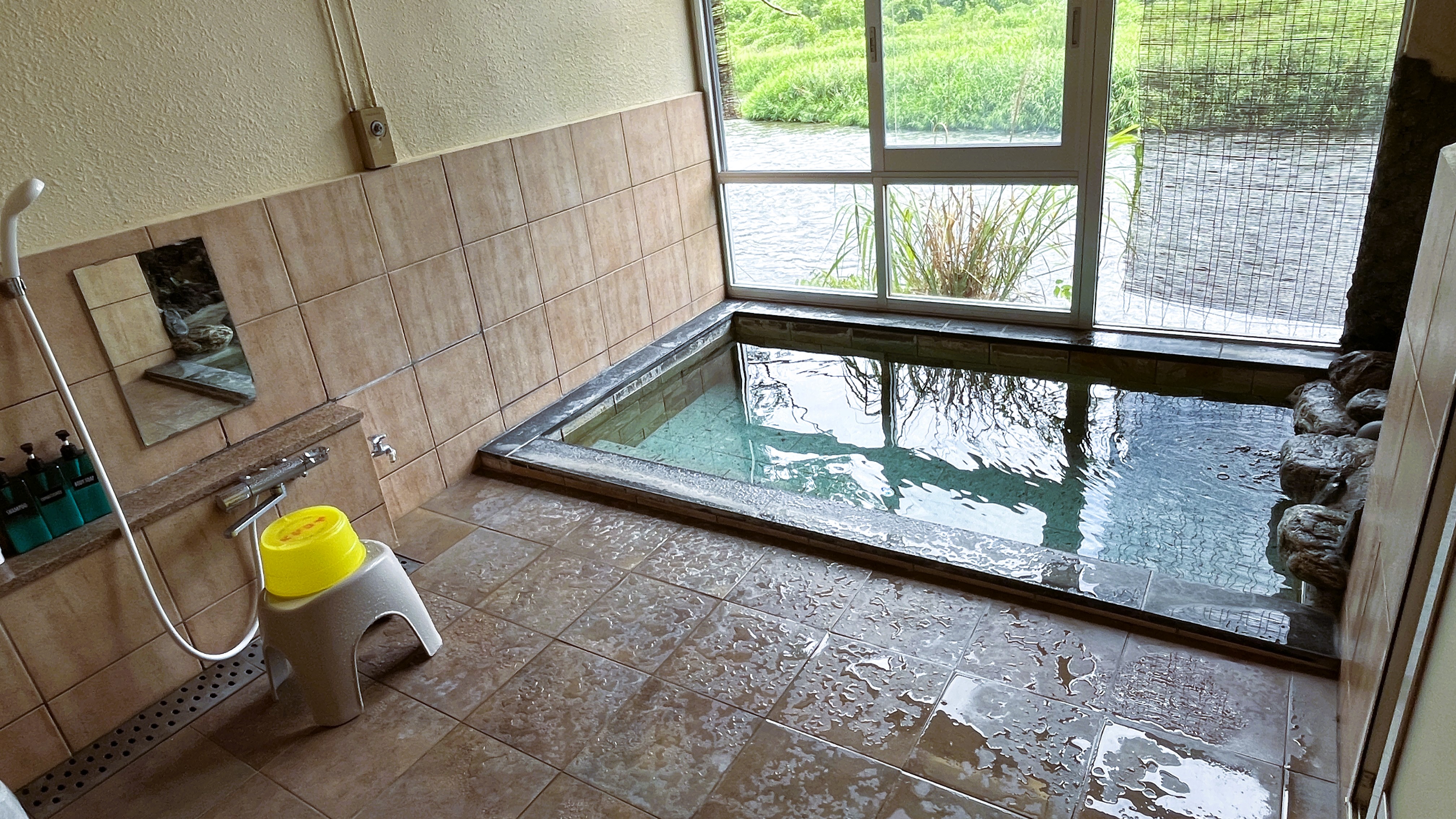 A tiled indoor bath with a rock-lined end.