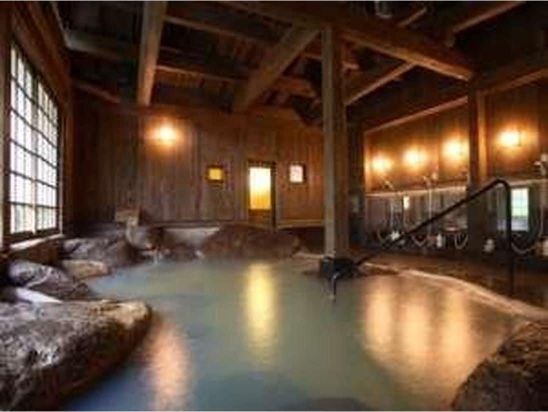 Kurokawa Onsen Yume Ryokan with a spacious indoor stone bath beneath exposed timber beams.