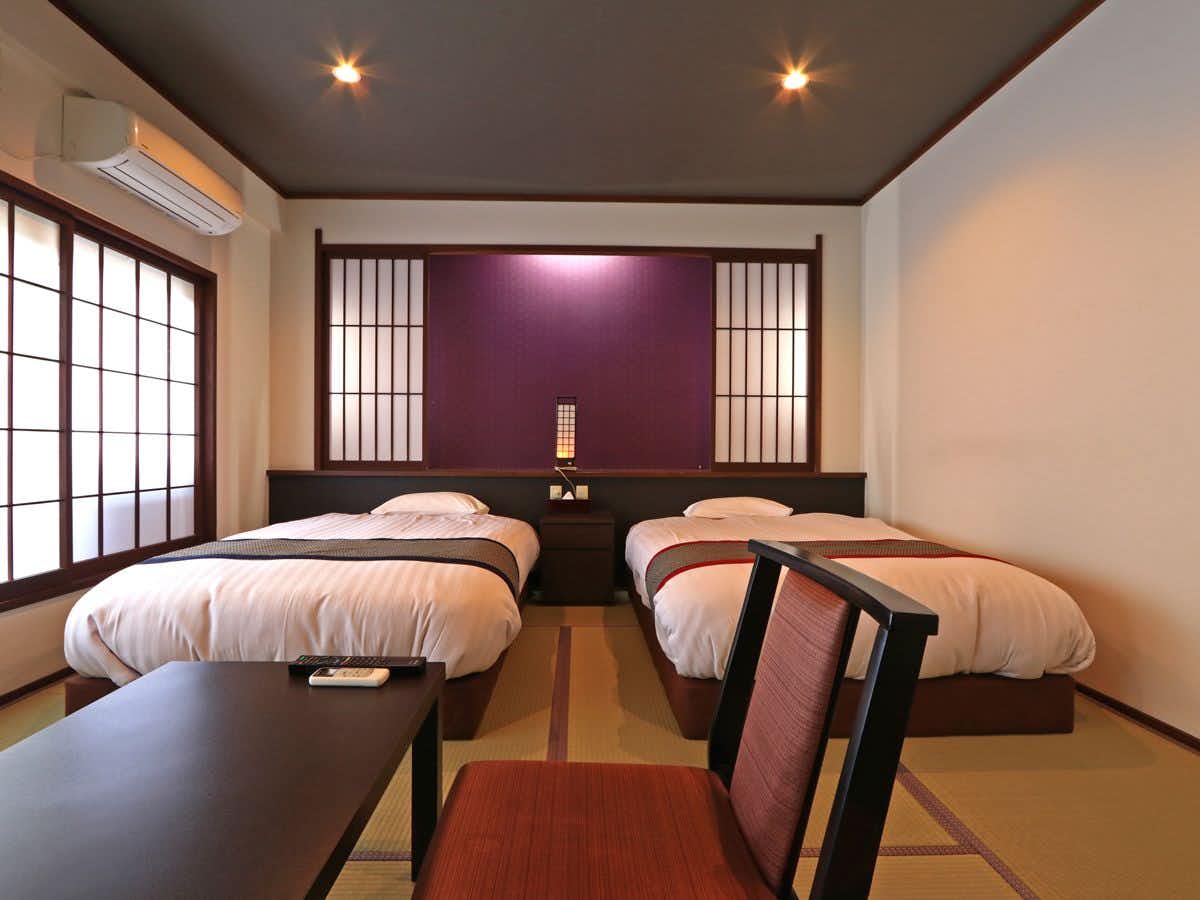 Masuya Ryokan a twin bedroom with a small table and purple accent wall.