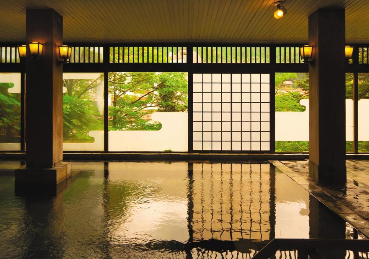 A reflective indoor bath opens toward a garden.