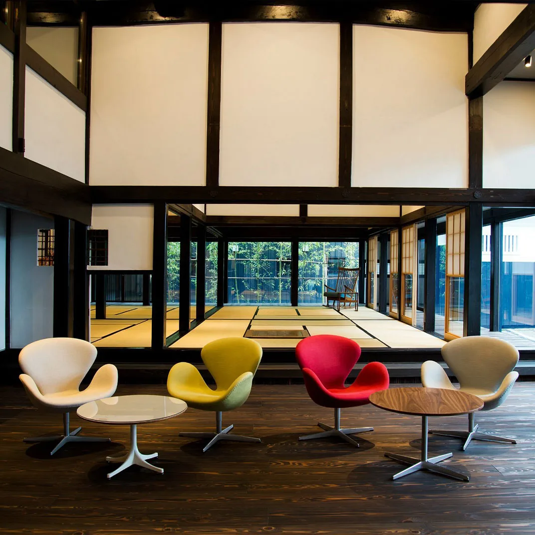 Colorful Swan chairs beneath original farmhouse beams in Takinami's lobby