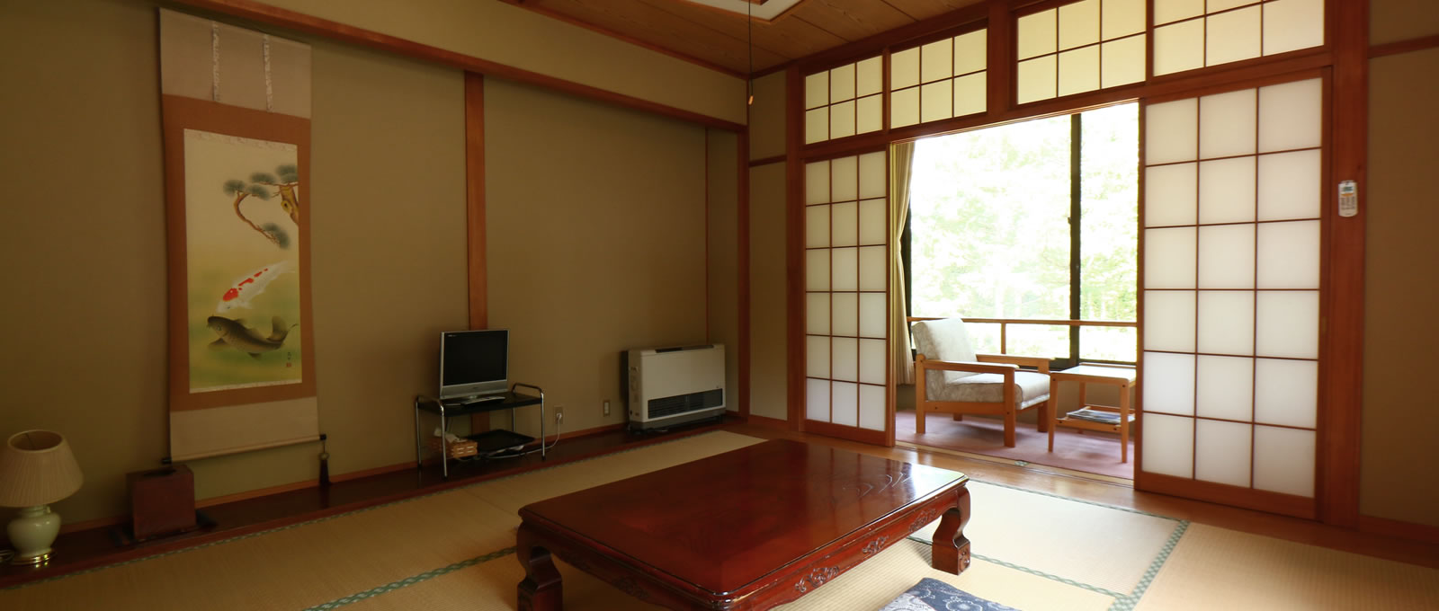 Tatami guest room with a low table, television and window-side chairs.