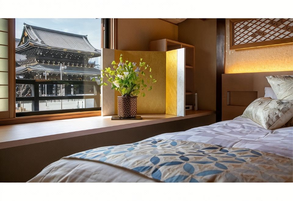 A guest bed beside a window overlooking a temple building.