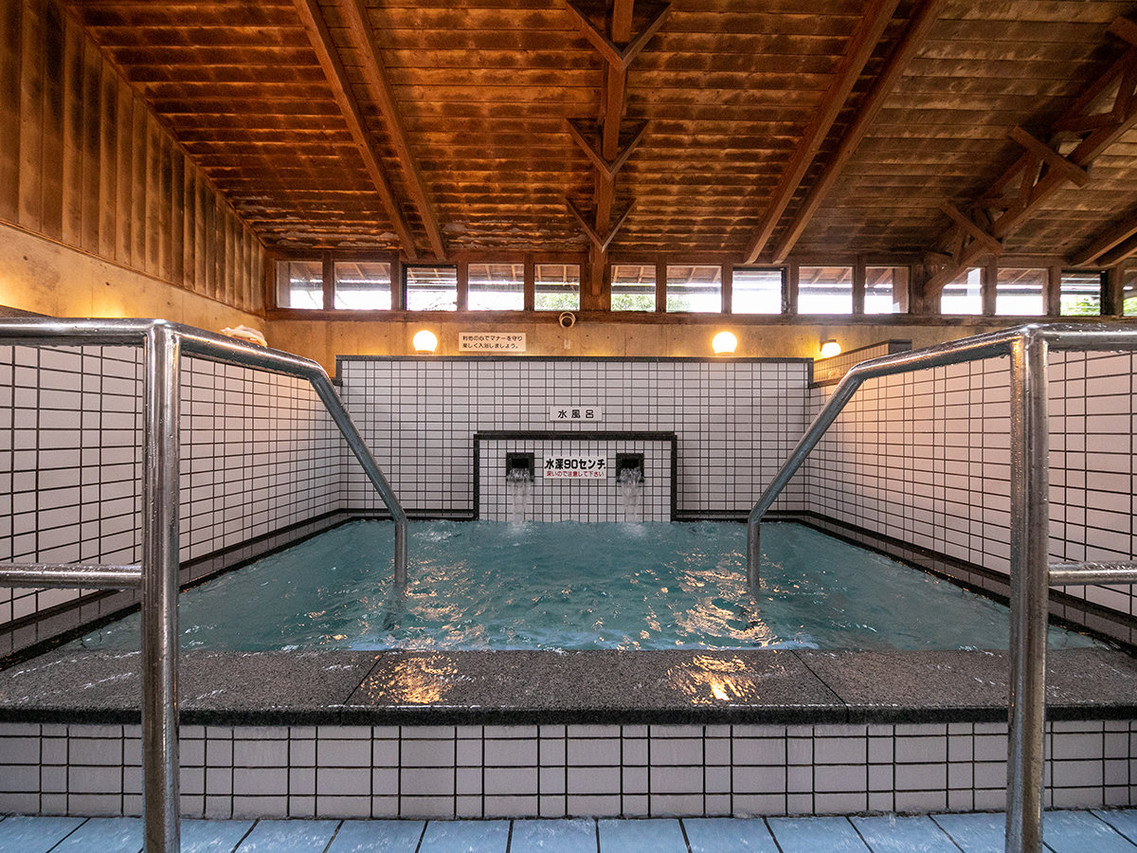 A tiled indoor bath sits beneath a timber ceiling.