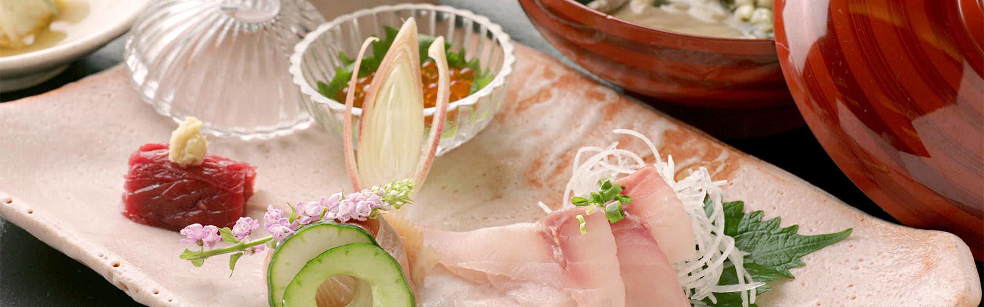 Ryokan Sakaya Sliced vegetables and prepared ingredients arranged on white plate with decorative bowls on pink fabric.