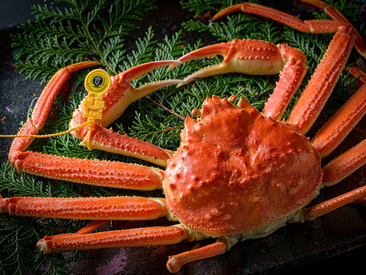 Ryokan Heisei with whole snow crab presented across dark ceramic plates.