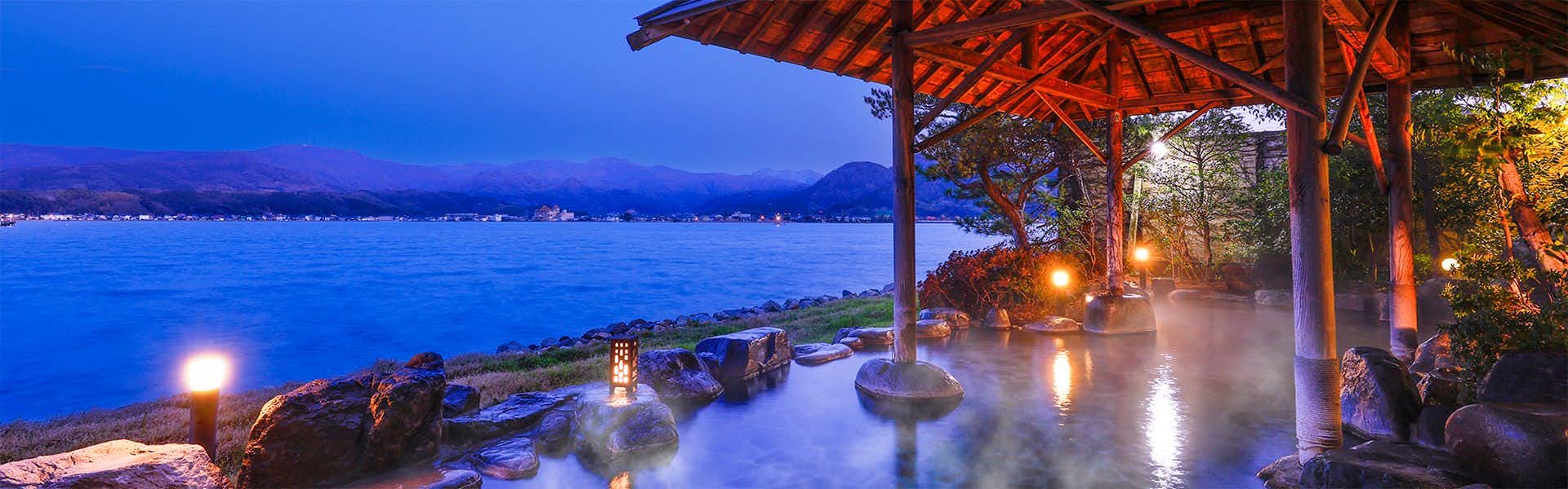 Hawaii Onsen Sennentei with an open-air rock bath overlooking calm lake water.