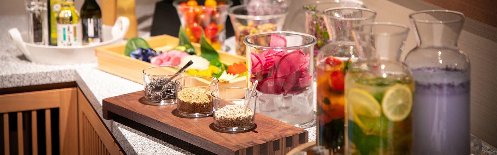 Sumihei Bettei Tokitoki Glasses with beverages and granular contents arranged on wooden board, flowers in background arrangement