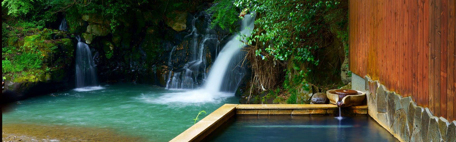 Oyado Kafugetsu with a turquoise bath beside a small forest waterfall.