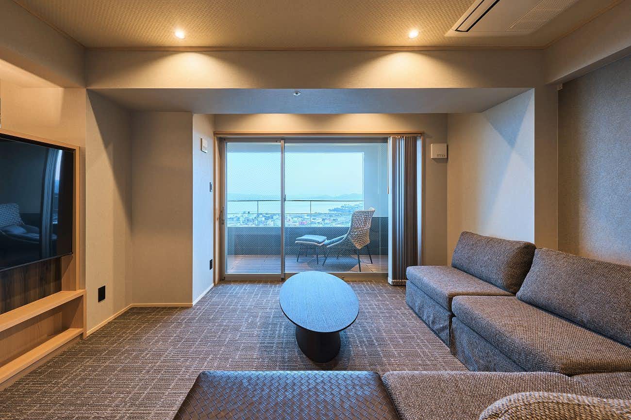 Sato-yu Mukashibanashi Yuzanso with a modern sitting room with sofa and a broad view window.