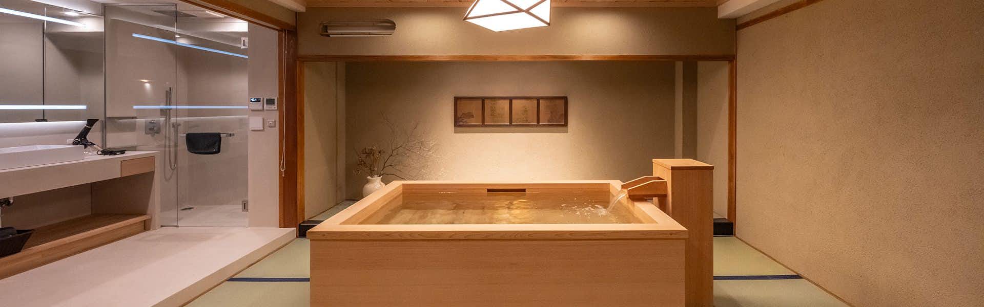 A square timber bath inside a calm tatami room.