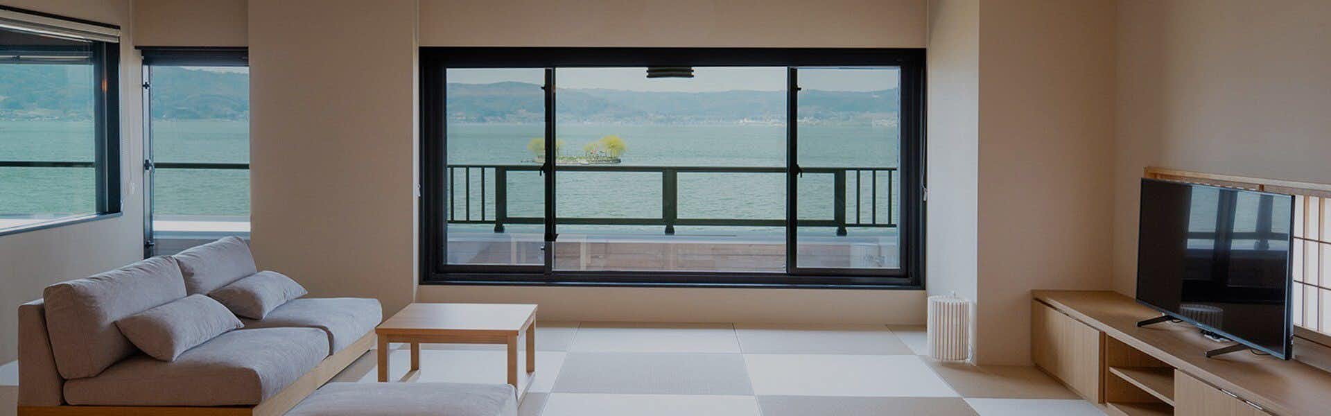 SUHAKU with a contemporary guest room framing Lake Suwa through broad windows.