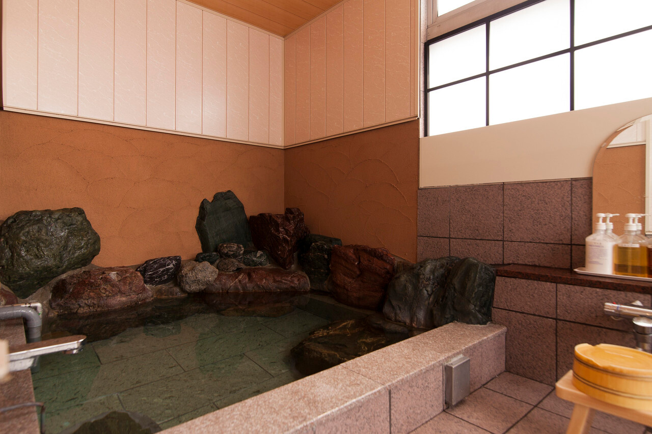Indoor bath with rocks and a shower area.