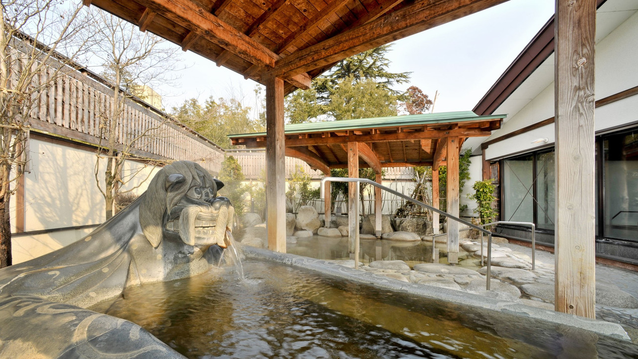 An outdoor bath with rocks and a seated statue.