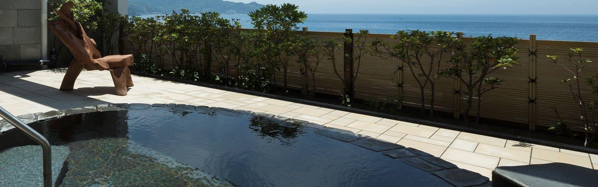 Akaneiro no Umi Arujisu with this scene, where an infinity-edge open-air bath looks across hedges toward the blue sea.