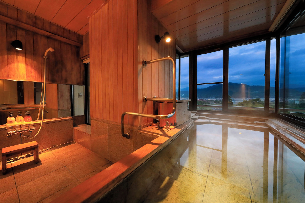 A wood-lined bath opens toward distant hills.