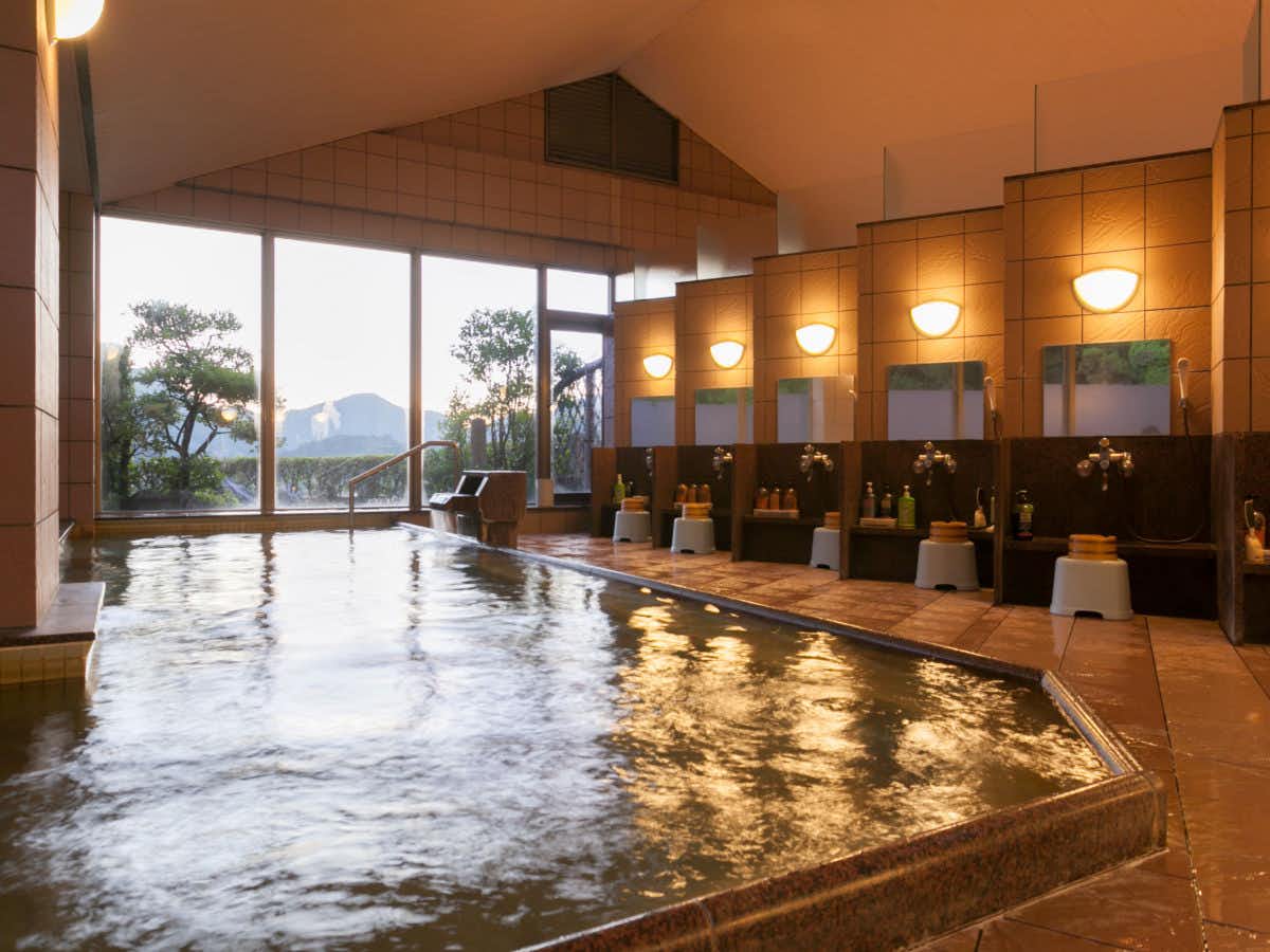 Yunogo Onsen Yasashisa no Yado Chikutei with an indoor bath reflecting warm ceiling lights and mountain views.