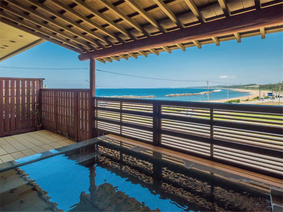 Hareya Ryokan with an open-air bath overlooking the shoreline through timber railings.