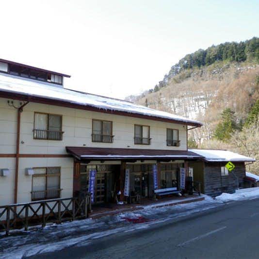 Fukando Kurumisawa Ryokan with the long roadside facade backed by a snowy hillside.