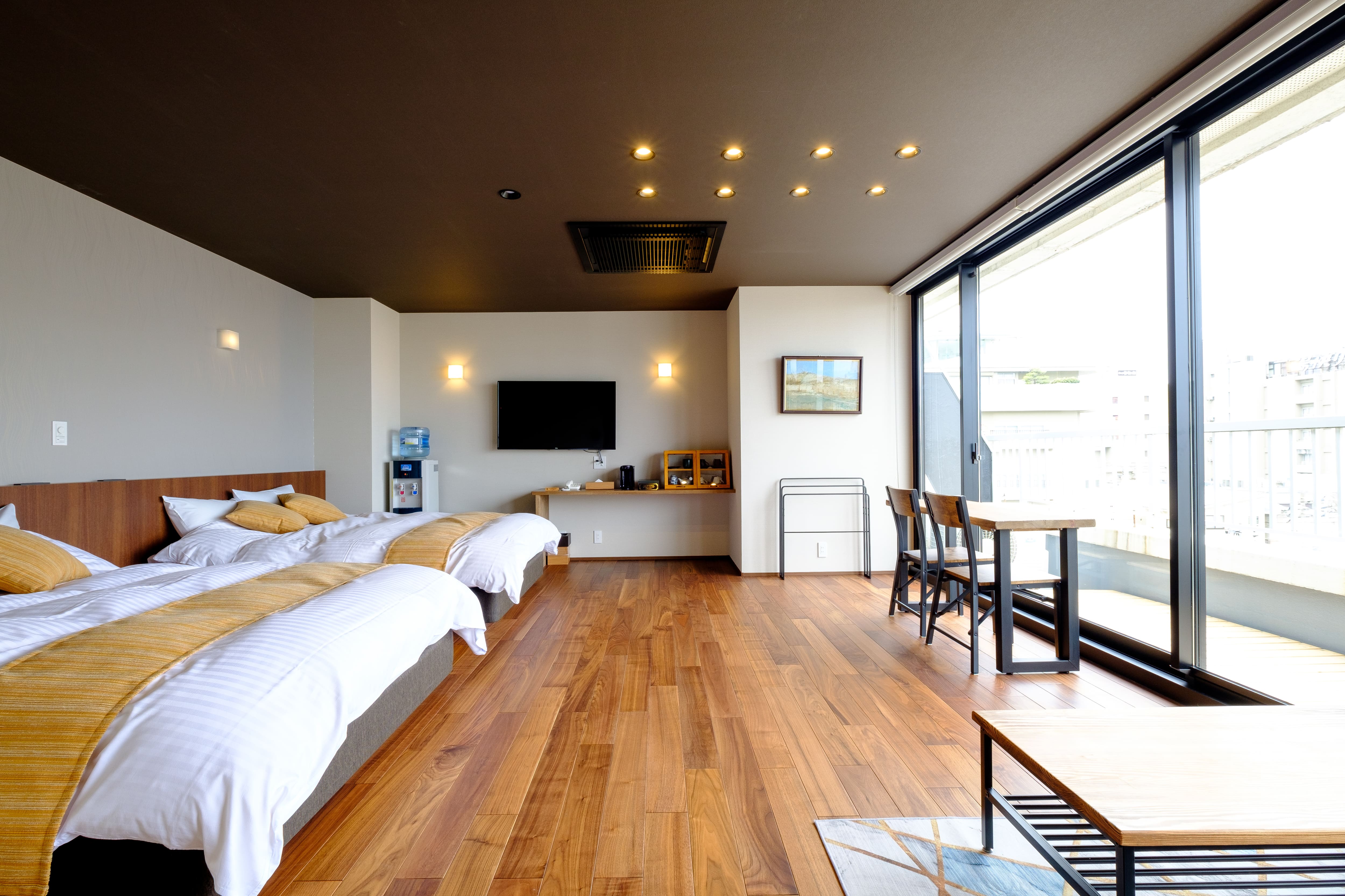 A spacious twin bedroom with wooden flooring and floor-to-ceiling windows.